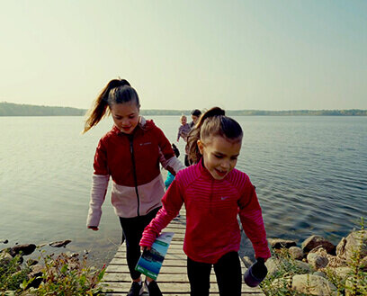 Action shot of Danielle's daughters walking towards the camera with a lake in the background.
